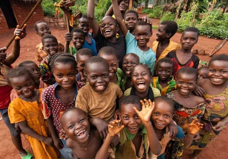 Joyful children smiling and waving at the camera outdoors.